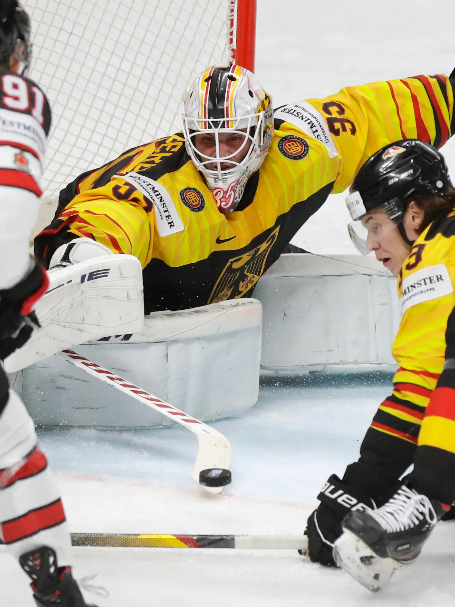 Canada's Cole Perfetti, left, challenges for the puck with Germany's goaltender Mathias Niederberger, centre, and Germany's Moritz Seider during the Ice Hockey World Championship group B match between Germany and Canada at the Arena in Riga, Latvia, Monday, May 24, 2021. (AP Photo/Sergei Grits)