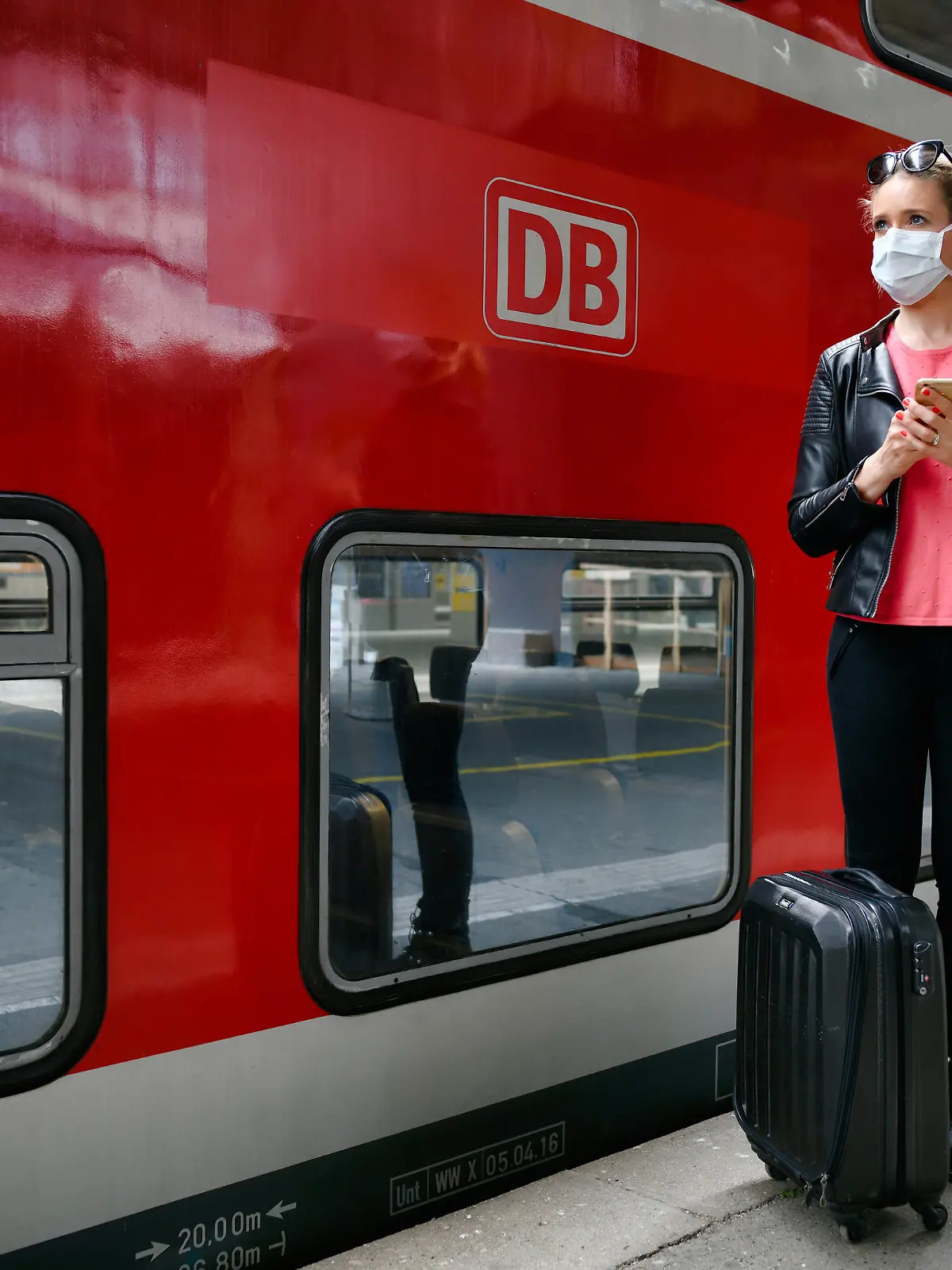 Frau mit Mundschutzmaske, wartet auf Zug