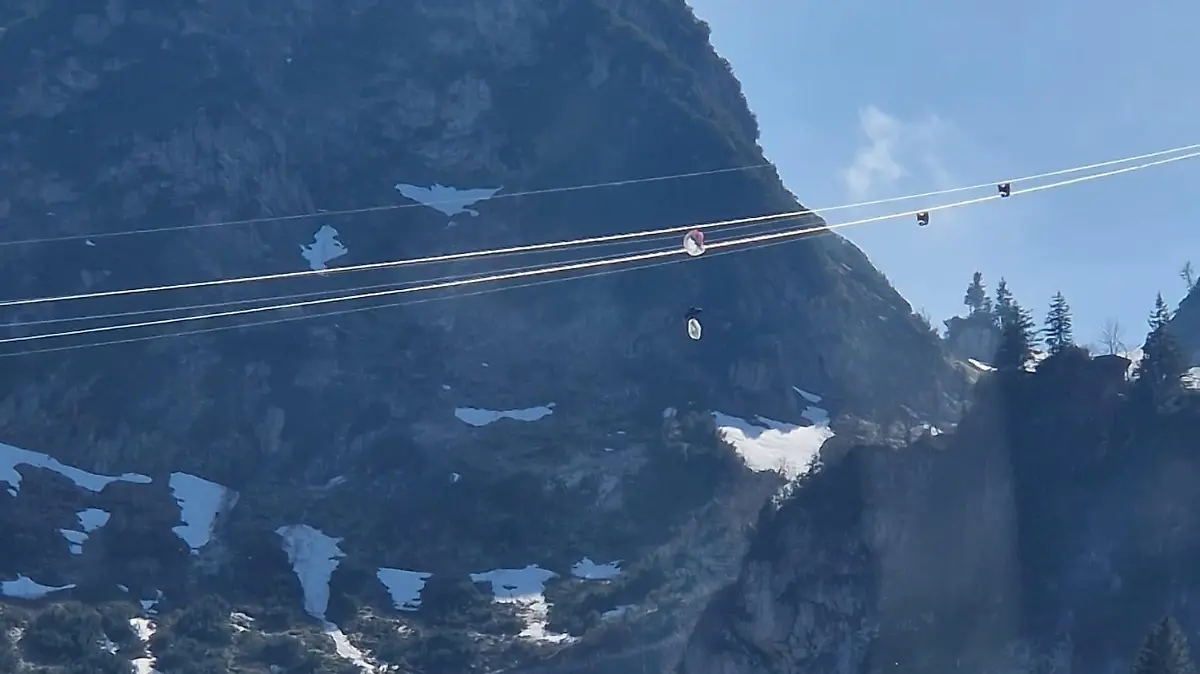 HANDOUT - 04.05.2023, Bayern, Bergen: Ein Gleitschirmflieger hängt in den Seilen einer Seilbahn in Oberbayern. Der Mann hatte sich an der höchsten Stelle der Hochfelln-Seilbahn in Bergen im Chiemgau rund 80 Meter über dem Boden mit seinem Fluggerät in den Stahlseilen verfangen. (zu dpa: «Gleitschirmflieger verfängt sich in Seilbahn - dramatischer Einsatz») Foto: -/Bergwacht Bayern/BW Bergen/dpa - ACHTUNG: Nur zur redaktionellen Verwendung im Zusammenhang mit der aktuellen Berichterstattung und nur mit vollständiger Nennung des vorstehenden Credits +++ dpa-Bildfunk +++