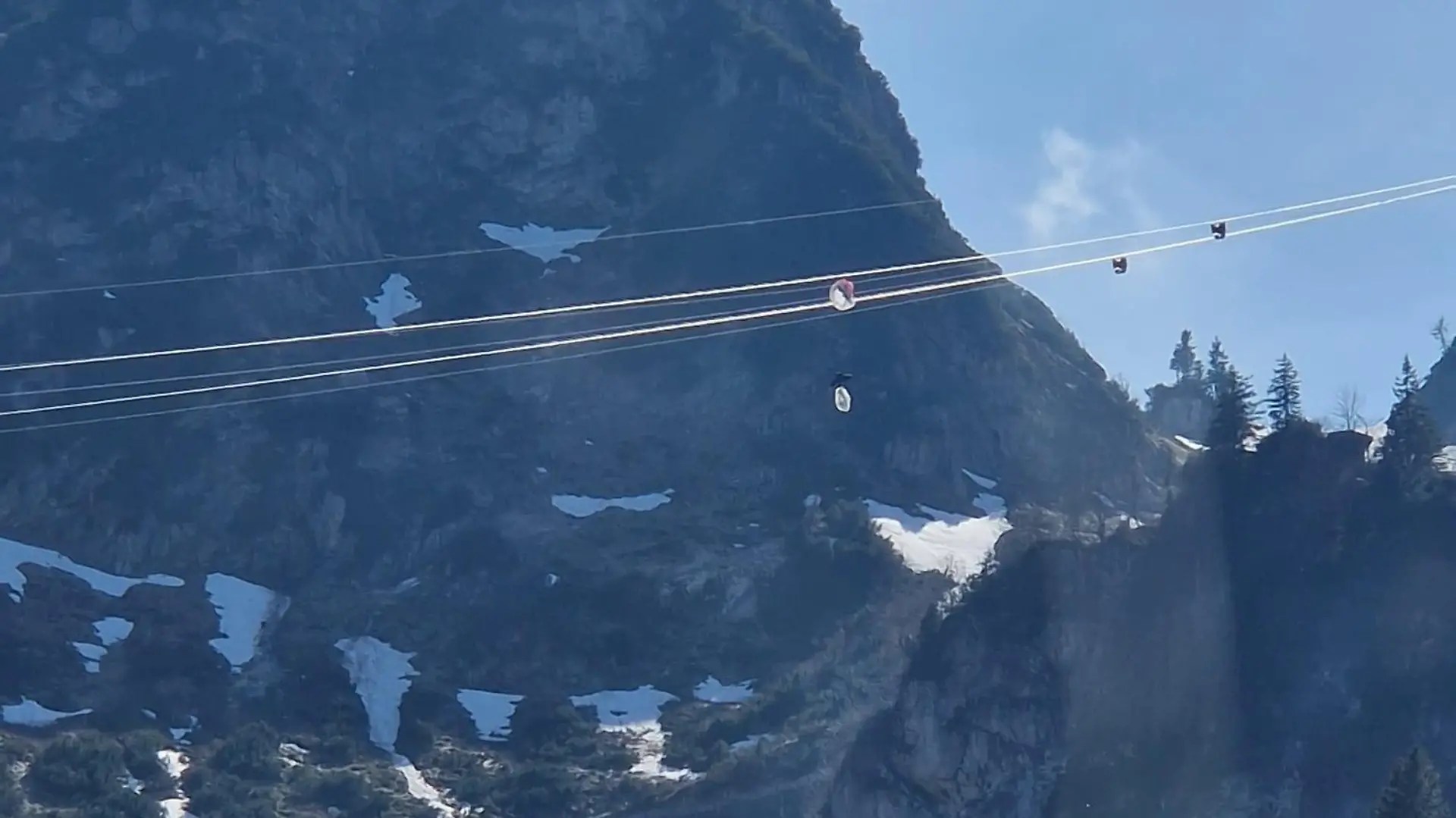 HANDOUT - 04.05.2023, Bayern, Bergen: Ein Gleitschirmflieger hängt in den Seilen einer Seilbahn in Oberbayern. Der Mann hatte sich an der höchsten Stelle der Hochfelln-Seilbahn in Bergen im Chiemgau rund 80 Meter über dem Boden mit seinem Fluggerät in den Stahlseilen verfangen. (zu dpa: «Gleitschirmflieger verfängt sich in Seilbahn - dramatischer Einsatz») Foto: -/Bergwacht Bayern/BW Bergen/dpa - ACHTUNG: Nur zur redaktionellen Verwendung im Zusammenhang mit der aktuellen Berichterstattung und nur mit vollständiger Nennung des vorstehenden Credits +++ dpa-Bildfunk +++