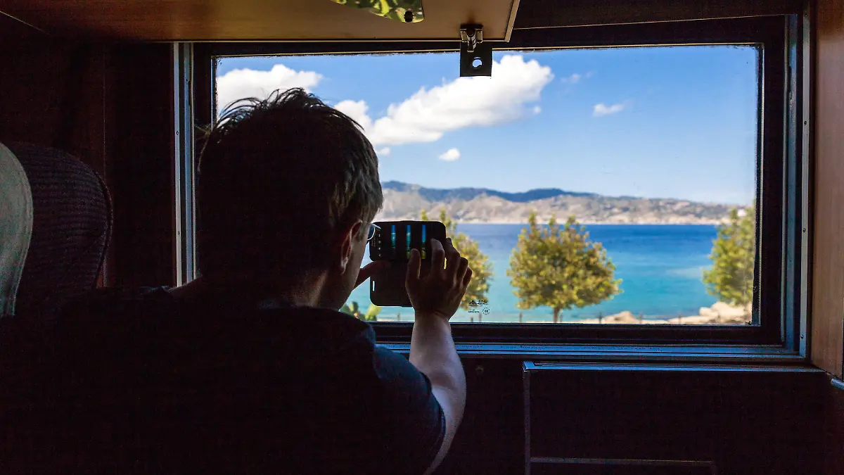 Aussicht aus dem Nachtzug zwischen Mailand und Palermo. Das Mittelmeer ist aus dem Fenster heraus zu sehen. Ein Fahrgast macht ein Foto mit seinem Smartphone. || Mindestpreis 0 Euro 