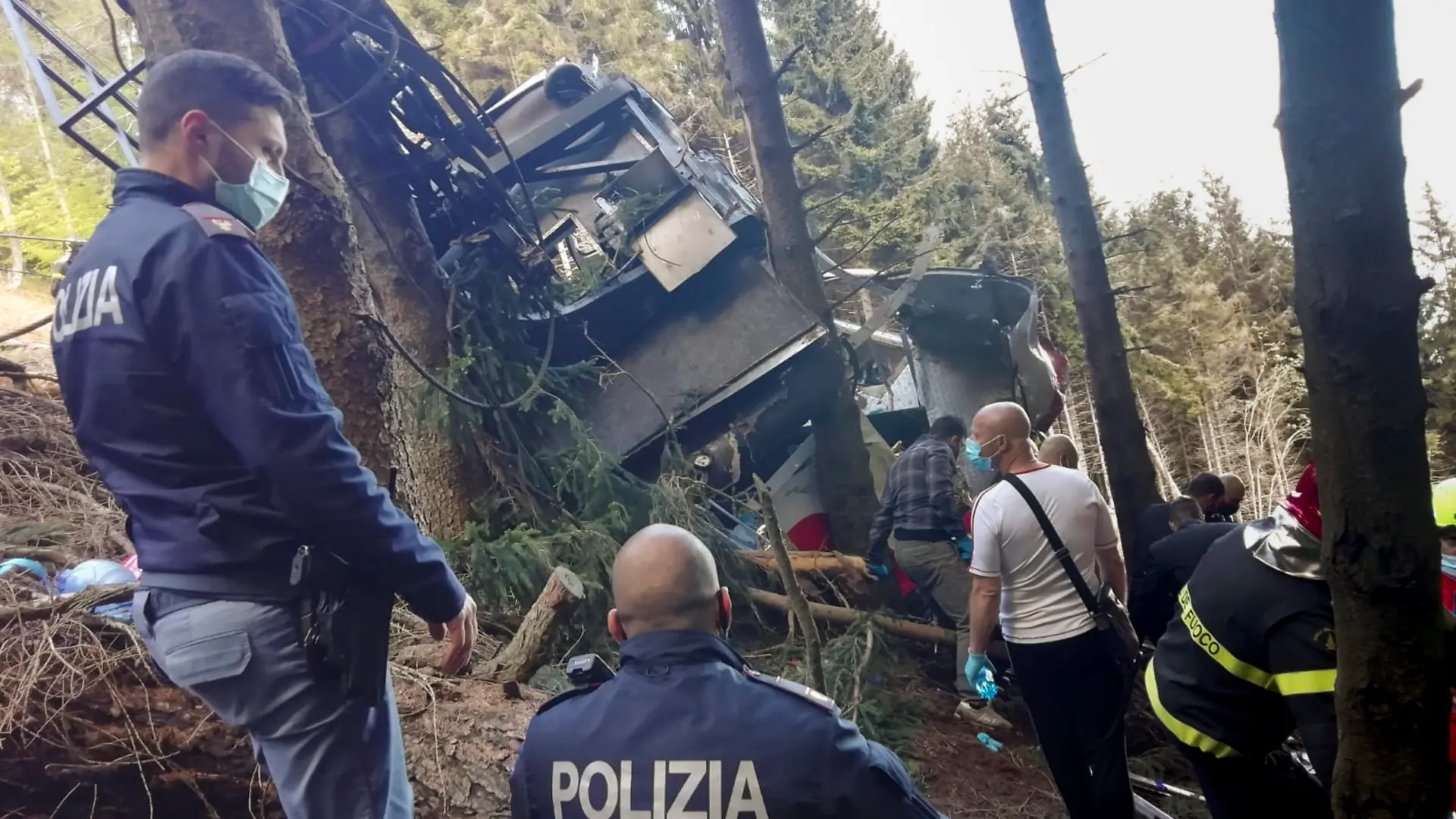 Rescuers work by the wreckage of a cable car after it collapsed near the summit of the Stresa-Mottarone line in the Piedmont region, northern Italy, Sunday, May 23, 2022. A cable car taking visitors to a mountaintop view of some of northern Italy's most picturesque lakes plunged to the ground Sunday, killing at least nine people and sending two children to the hospital, authorities said. (Italian Police via AP)