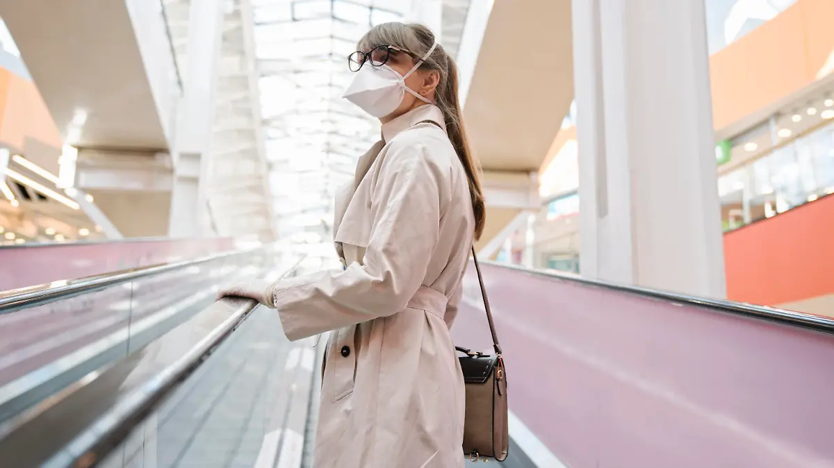  Woman with face mask and disposable gloves on an escalator in a shopping center model released Symbolfoto AHSF02593