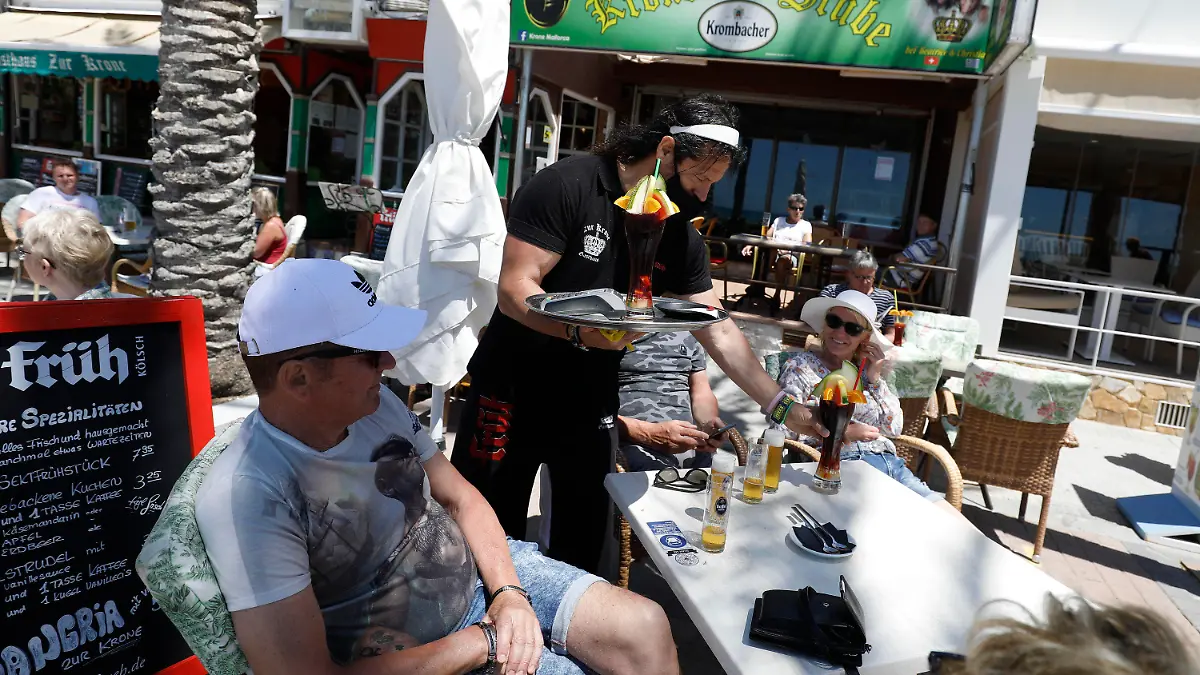 13.05.2021, Spanien, Palma: Christian, Kellner im Gasthaus Zur Krone, serviert Wolfgang und Belinda einen Drink. Viele Flüge aus Deutschland werden zu Christi Himmelfahrt auf der Insel erwartet. Foto: Clara Margais/dpa +++ dpa-Bildfunk +++