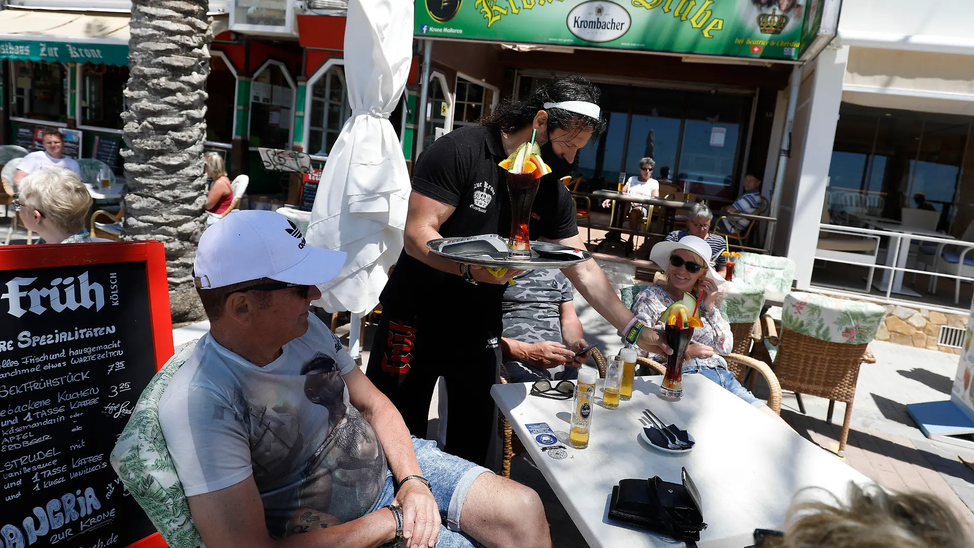 13.05.2021, Spanien, Palma: Christian, Kellner im Gasthaus Zur Krone, serviert Wolfgang und Belinda einen Drink. Viele Flüge aus Deutschland werden zu Christi Himmelfahrt auf der Insel erwartet. Foto: Clara Margais/dpa +++ dpa-Bildfunk +++