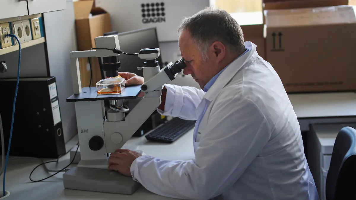 FILE - Belgian top virologist Marc Van Ranst looks into a microscope at his lab in Leuven, Belgium, Feb. 19, 2020. The hunt for an armed man who is on a Belgian terror watch list because of his extreme right sympathies and who had threatened several people, including top virologist Marc Van Ranst, entered a second day on Wednesday, May 19, 2021. Justice Minister Vincent Van Quickenborne described the man as an "acute threat" and is known for his extreme right sympathies. (AP Photo/Francisco Seco)
