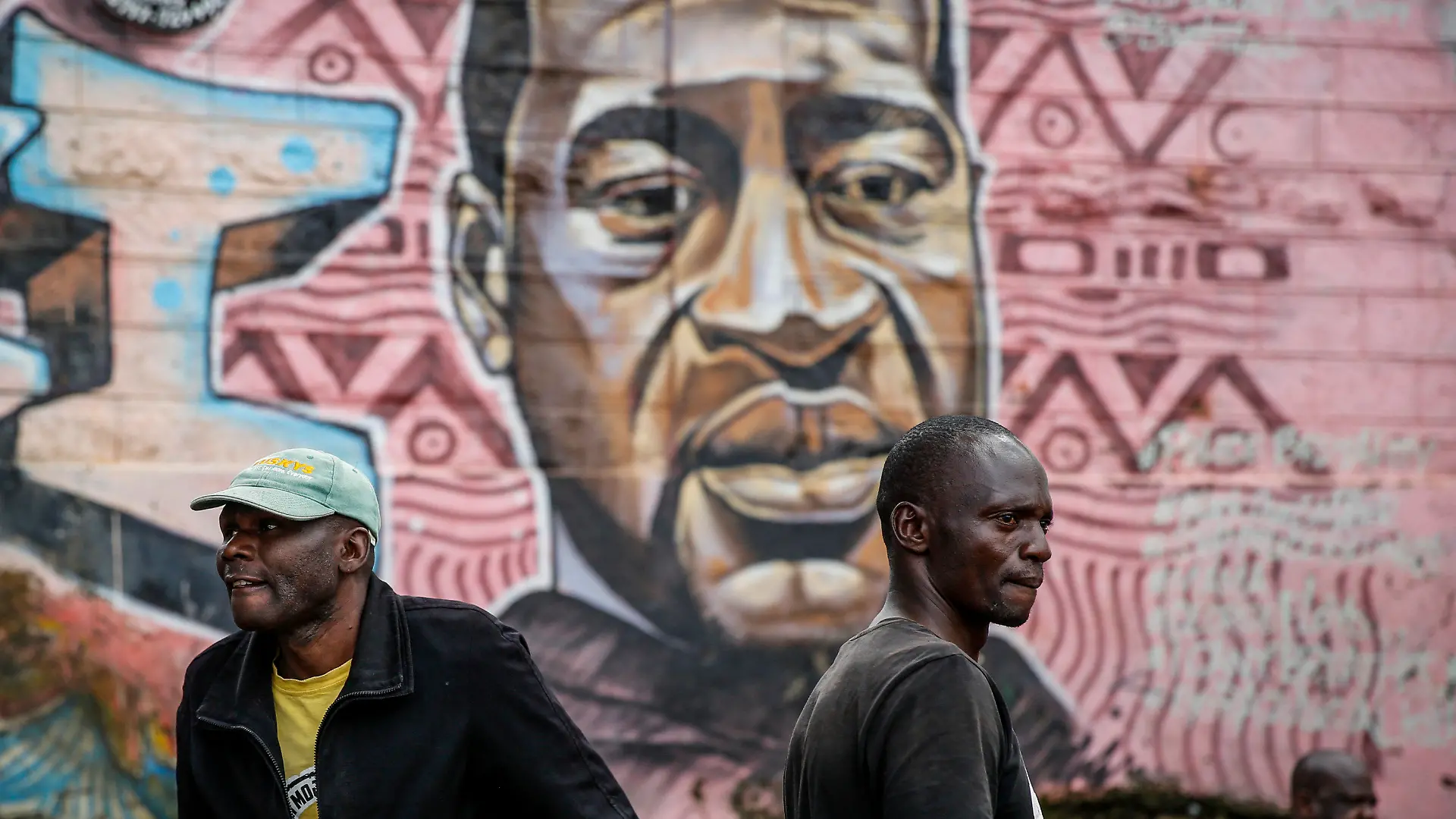 Local residents stand next to a mural painted in June 2020 showing George Floyd with the Swahili word "Haki" or "Justice" in the Kibera low-income neighborhood of Nairobi, Kenya, Wednesday, April 21, 2021. After three weeks of testimony, the trial of the former police officer charged with killing George Floyd ended swiftly: barely over a day of jury deliberations, then just minutes for the verdicts to be read — guilty, guilty and guilty — and Derek Chauvin was handcuffed and taken away to prison. The guilty verdict in the George Floyd trial was not just America's victory. It signaled hope for those seeking racial justice and fighting police brutality across the Atlantic. (AP Photo/Brian Inganga)