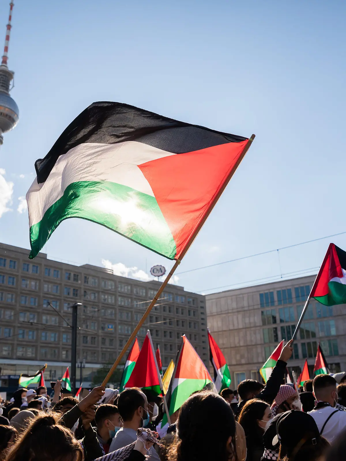 19.05.2021, Berlin: Teilnehmer einer Demonstration unter dem Motto «Gegen die israelische Aggression in Palästina» haben sich mit Fahnen auf dem Alexanderplatz versammelt. Foto: Christoph Soeder/dpa +++ dpa-Bildfunk +++