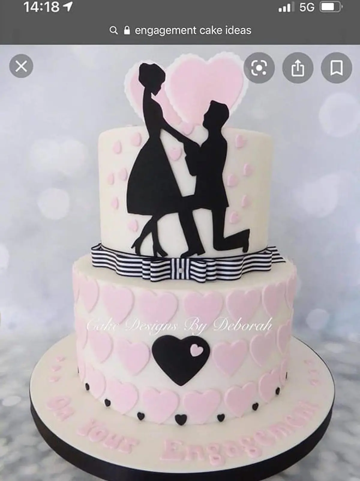 Eine mehrstöckige Torte in weiß, mit einem Miniatur-Brautpaar oben auf dem Kuchen, die für besondere Anlässe wie Verlobungen oder Hochzeiten angeboten wird.