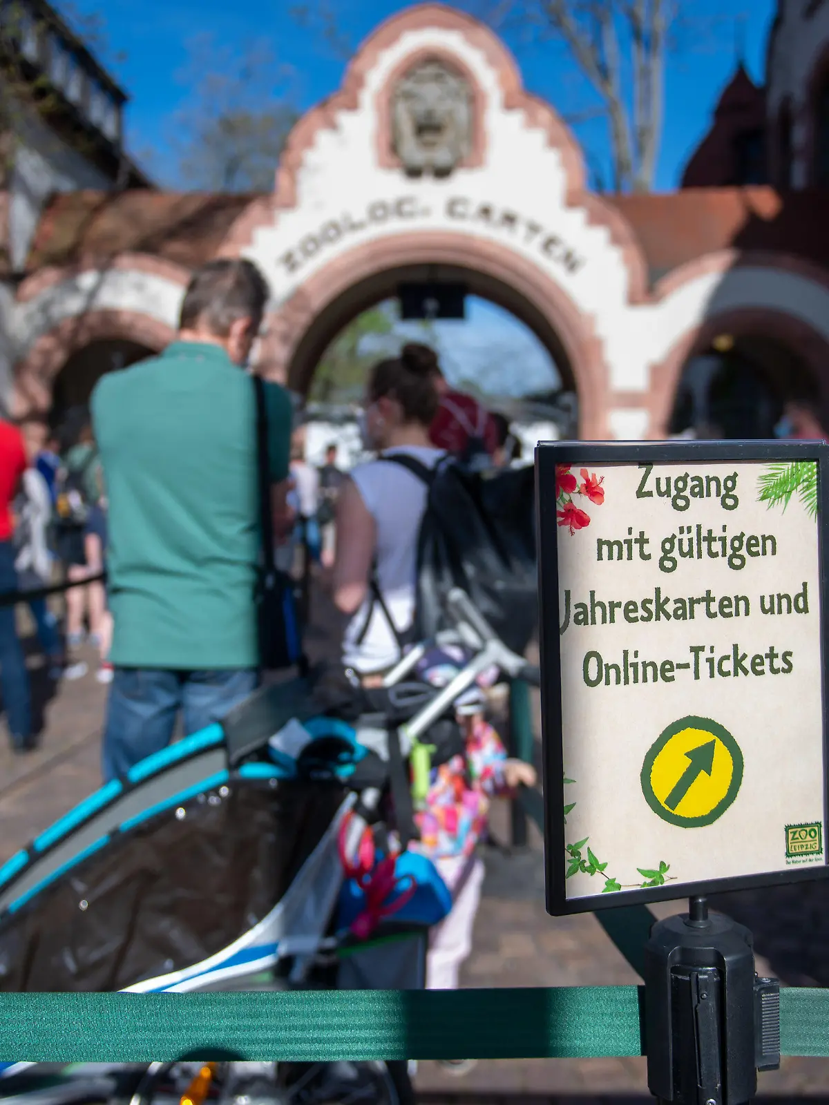 ARCHIV - 10.05.2021, Sachsen, Leipzig: Ein Schild mit der Aufschrift ·Zugang mit gültigen Jahreskarten und Online-Tickets· steht vor einer Besucher-Schlange am Eingang zum Zoo Leipzig. (zu dpa: Andrang in sächsische Zoos zu Pfingsten überschaubar) Foto: Hendrik Schmidt/dpa-Zentralbild/dpa +++ dpa-Bildfunk +++