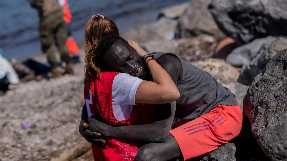 18.05.2021, Spanien, Ceuta: Ein Mitglied des Spanischen Roten Kreuzes tröstet einen Migranten, und umarmt ihn am Strand in der spanischen Enklave Ceuta. Spanien soll bereits 2700 der gut 6000 vom Gebiet Marokkos aus in Ceuta eingedrungenen Menschen wieder nach Marokko abgeschoben haben. Foto: Bernat Armangue/AP/dpa +++ dpa-Bildfunk +++