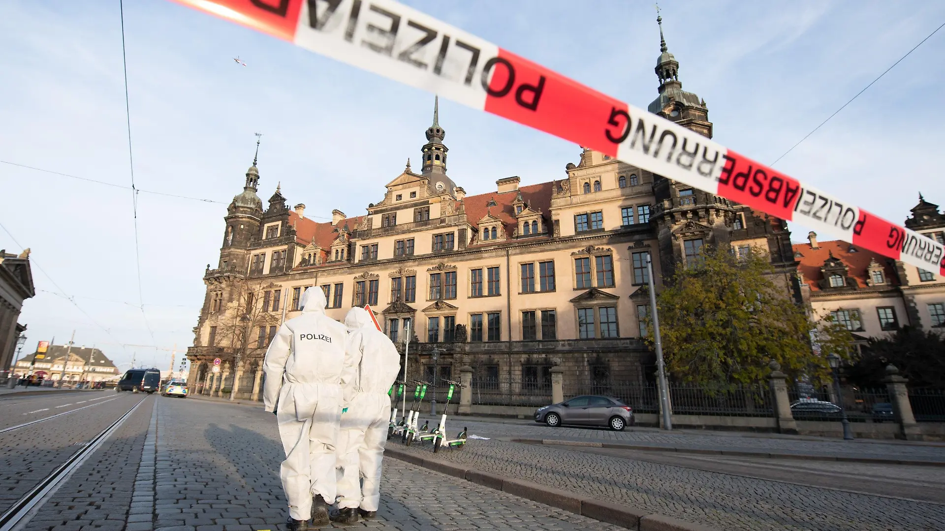 ARCHIV - 25.11.2019, Sachsen, Dresden: Zwei Mitarbeiter der Spurensicherung stehen vor dem Residenzschloss mit dem Grünen Gewölbe hinter einem Absperrband. (zu «Nach Einbruch in Grünes Gewölbe: Museen beraten Sicherheit") Foto: Sebastian Kahnert/zb/dpa +++ dpa-Bildfunk +++