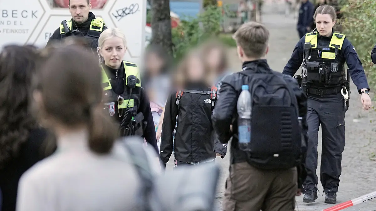 03.05.2023, Berlin: Polizisten bringen Kinder weg. Zwei Schulkinder sind am Mittwoch in einer Schule in Berlin-Neukölln vermutlich von einem Mann verletzt worden. Eins von ihnen sei lebensgefährlich, das andere schwer verletzt, sagte eine Polizeisprecherin am Nachmittag. Foto: Michael Kappeler/dpa - ACHTUNG: Person(en) wurde(n) aus rechtlichen Gründen gepixelt +++ dpa-Bildfunk +++