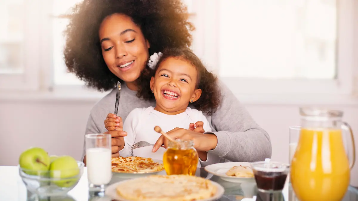 African-American young mother and daughter having breakfast