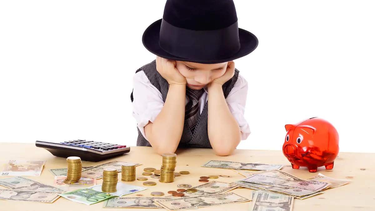 Ein kleine Junge sitzt am Tisch und zählt sein Geld. Man sieht einen Taschenrechner und ein Sparschwein.