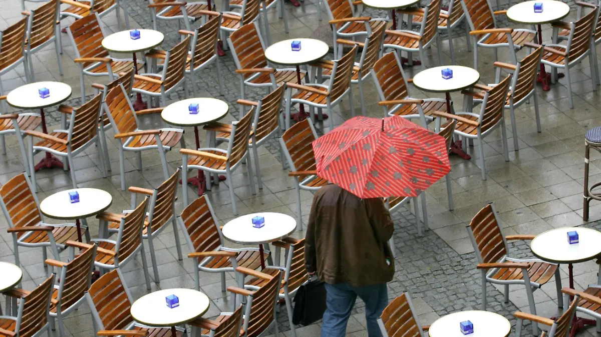Ein Passant geht in Magdeburg mit Regenschirm durch einen leeren Biergarten (Foto vom 07.05.2007). Nach der wochenlangen Trockenheit sorgt regnerisches Wetter für Abkühlung und natürliche Bewässerung. Foto: Jens Wolf dpa/lah +++(c) dpa - Bildfunk+++