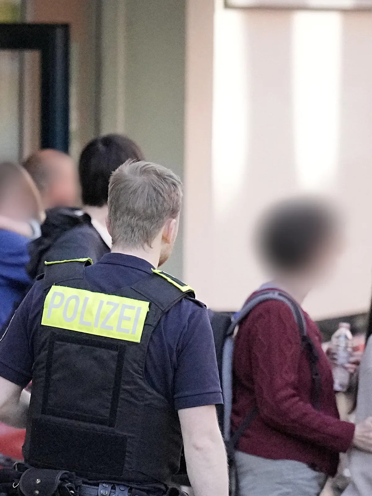 03.05.2023, Berlin: Menschen stehen vor der Schule in Neukölln . Zwei Schulkinder sind am Mittwoch in einer Schule in Berlin-Neukölln vermutlich von einem Mann verletzt worden. Eins von ihnen sei lebensgefährlich, das andere schwer verletzt, sagte eine Polizeisprecherin am Nachmittag. Foto: Michael Kappeler/dpa - ACHTUNG: Person(en) wurde(n) aus rechtlichen Gründen gepixelt +++ dpa-Bildfunk +++