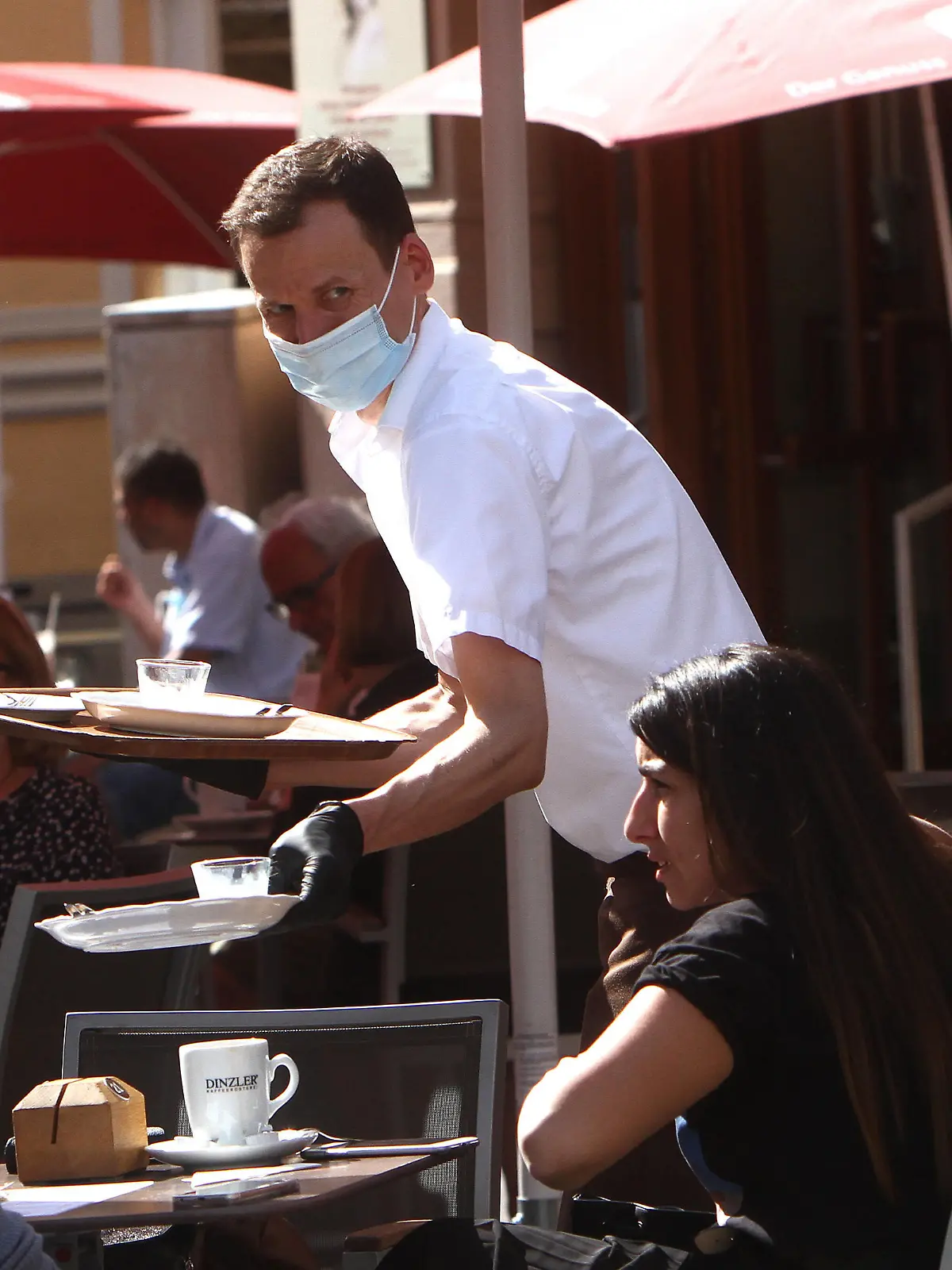  Seit dem heutigen Tage, dem 18.05.2020, dürfen in Bayern unter strengen Auflagen Biergärten und Restaurants wieder Gäste im Außenbereich bewirten, was trotz des warmen und sonnigen Frühlingstag s nicht immer zu vollen Tischen führt: die neuen Regeln zur Hygiene beinhalten eine Desinfektionspflicht von Hände n, Speisekarte n und Tische n sowie die Einhaltung eines Mindesabstands von 1,50 Meter zwischen den Tischen. Das Personal muss zwingend eine Mund-Nasen Schutzmaske und Handschuhe tragen, wie es hier ein Kellner in einem geöffneten Caf in der Innenstadt von Würzburg praktiziert, Bayern, Deutschland. *** As of today, 18 05 2020, beer gardens and restaurants in Bavaria are again allowed to serve guests outdoors under strict conditions, which does not always lead to full tables despite the warm and sunny spring day The new rules on hygie
