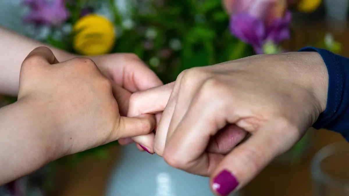 ARCHIV - 07.05.2021, Sachsen, Leipzig: Eine Mutter hält die Hand ihrer Tochter. Familien sollen die Möglichkeit erhalten, die Namen aller sorgeberechtigten Elternteile in den Pass des Kindes eintragen zu lassen. Das sieht eine Vorlage aus dem Bundesinnenministerium vor, über die das Kabinett an diesem 12.05.2021 beraten will. Foto: Hendrik Schmidt/dpa-Zentralbild/dpa +++ dpa-Bildfunk +++