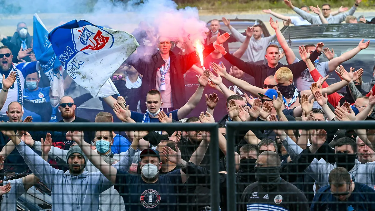 Fans des FC Hansa Rostock brenen nach dem Spiel vor dem Stadion Bengalos und Rauchbomben ab und feiern mit der Mannschaft die sich durch die Lücke auf der Tribüne zeigt, den Auswärtssieg, Bengalo, Bengalos, Feuerwerk, flare, Fans, Publikum, Zuschauer, Stimmung, Atmosphäre, Stadion, 15.05.2021, Unterhaching Deutschland, Fussball, 3. Liga, SpVgg Unterhaching - F.C. Hansa Rostock, DFB/DFL REGULATIONS PROHIBIT ANY USE OF PHOTOGRAPHS AS IMAGE SEQUENCES AND/OR QUASI-VIDEO. *** Fans of FC Hansa Rostock burn bengalos and smoke bombs outside the stadium after the match and celebrate the away victory with the team showing through the gap in the stands, bengalo, bengalos, fireworks, flare, fans, crowd, spectators, atmosphere, stadium, 15 05 2021, Unterhaching Germany , football, 3 Liga, SpVgg Unterhaching F C Hansa Rostock, DFB DFL REGULATES PROHIBIT ANY USE OF PHOTOGRAPHS AS IMAGE SEQUENCES AND OR QUASI VIDEO xslx