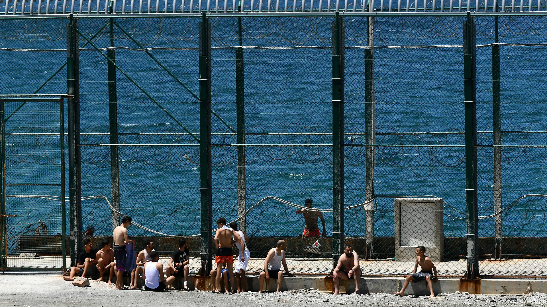 Men and children from Morocco sit after entering into the Spanish territory at the border of Morocco and Spain, at the Spanish enclave of Ceuta on Monday, May 17, 2021. Authorities in Spain say that around 1,000 Moroccan migrants have crossed into Spanish territory (Antonio Sempere/Europa Press via AP)