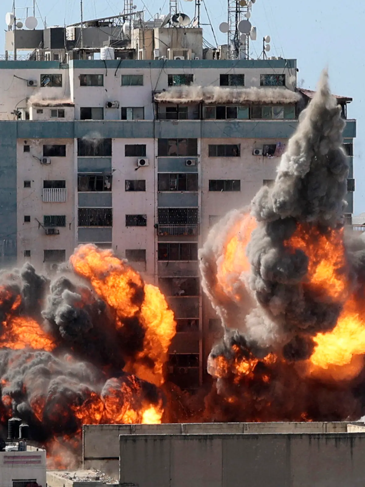 dpatopbilder - 15.05.2021, Palästinensische Autonomiegebiete, Gaza-Stadt: Rauch und Feuer steigen aus einem Gebäude auf, in dem verschiedene internationale Medien untergebracht sind, darunter auch die Associated Press und Al-Dschasira, nach einem israelischen Luftangriff. Die Nachrichtenagentur Associated Press (AP) hat entsetzt auf die Zerstörung eines Hochhauses mit ihrem Büro im Gazastreifen bei einem israelischen Luftangriff reagiert. Foto: Mahmud Hams/POOL AFP/AP/dpa +++ dpa-Bildfunk +++