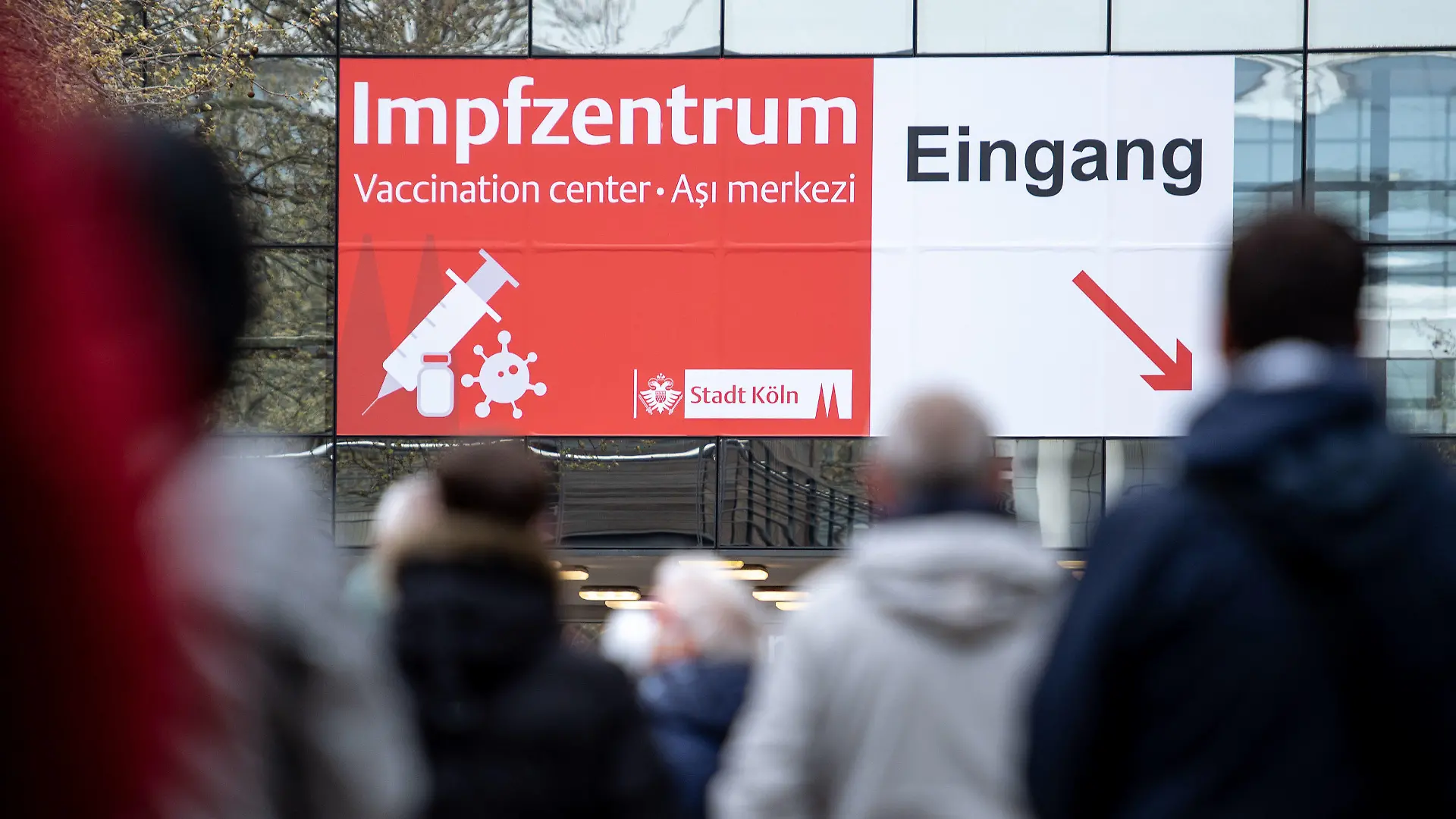 04.04.2021, Nordrhein-Westfalen, Köln: Menschen warten vor einem Impfzentrum. In Nordrhein-Westfalen können sich Menschen ab 60 Jahren seit diesem Wochenende mit dem Wirkstoff von Astrazeneca gegen das Coronavirus impfen lassen. Der Ansturm auf die Impf-Termine für die Altersgruppe 60 plus hatte schon am frühen Morgen des Karsamstag, 03.04.2021 zu überlasteten Leitungen am Telefon und im Internet geführt. Foto: Marius Becker/dpa +++ dpa-Bildfunk +++