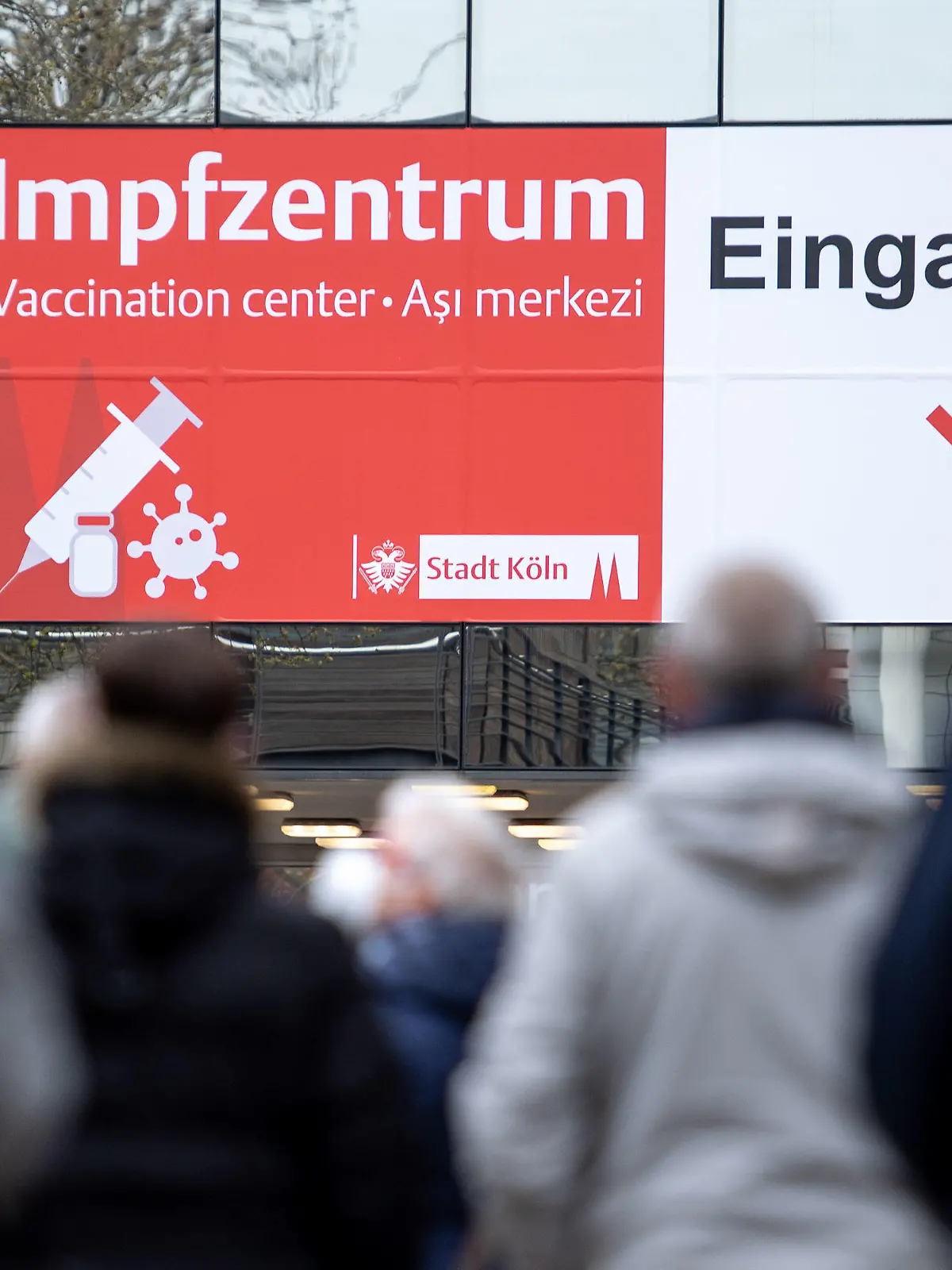 04.04.2021, Nordrhein-Westfalen, Köln: Menschen warten vor einem Impfzentrum. In Nordrhein-Westfalen können sich Menschen ab 60 Jahren seit diesem Wochenende mit dem Wirkstoff von Astrazeneca gegen das Coronavirus impfen lassen. Der Ansturm auf die Impf-Termine für die Altersgruppe 60 plus hatte schon am frühen Morgen des Karsamstag, 03.04.2021 zu überlasteten Leitungen am Telefon und im Internet geführt. Foto: Marius Becker/dpa +++ dpa-Bildfunk +++