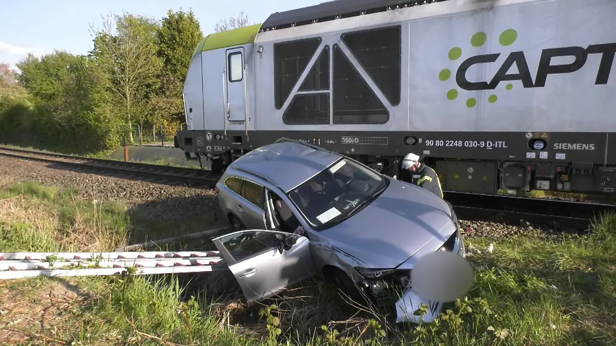 Ein grauer Mazda steht am Bahnübergang in Emden nach dem Unfall mit einem Güterzug neben den Gleisen.