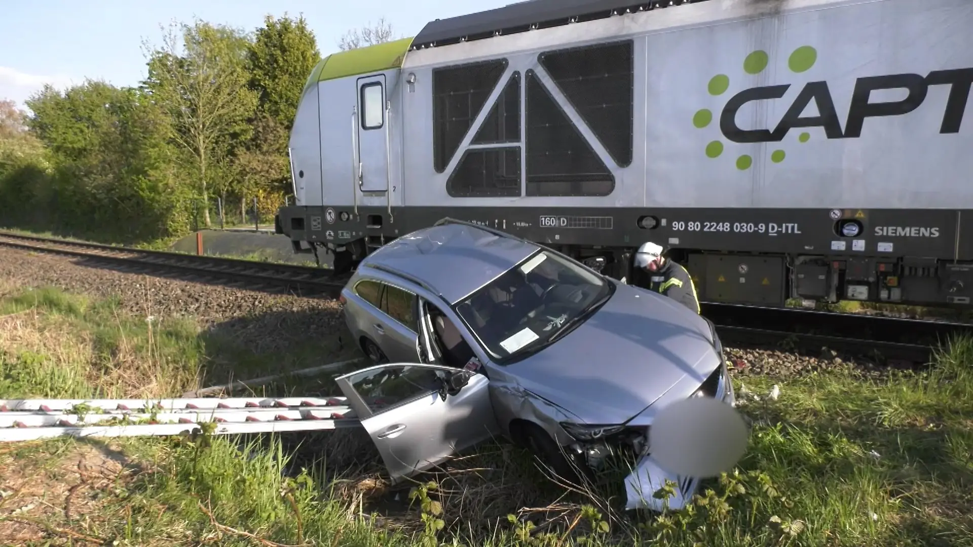 Ein grauer Mazda steht am Bahnübergang in Emden nach dem Unfall mit einem Güterzug neben den Gleisen.