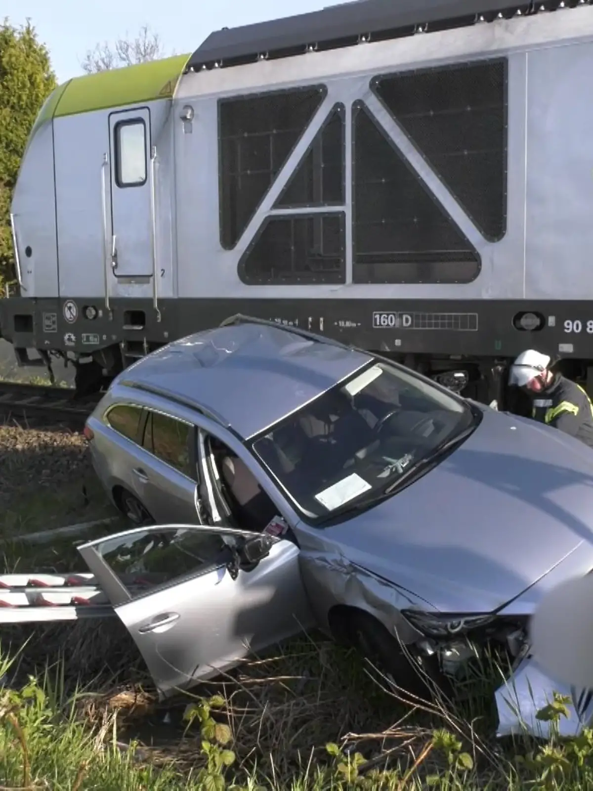 Ein grauer Mazda steht am Bahnübergang in Emden nach dem Unfall mit einem Güterzug neben den Gleisen.