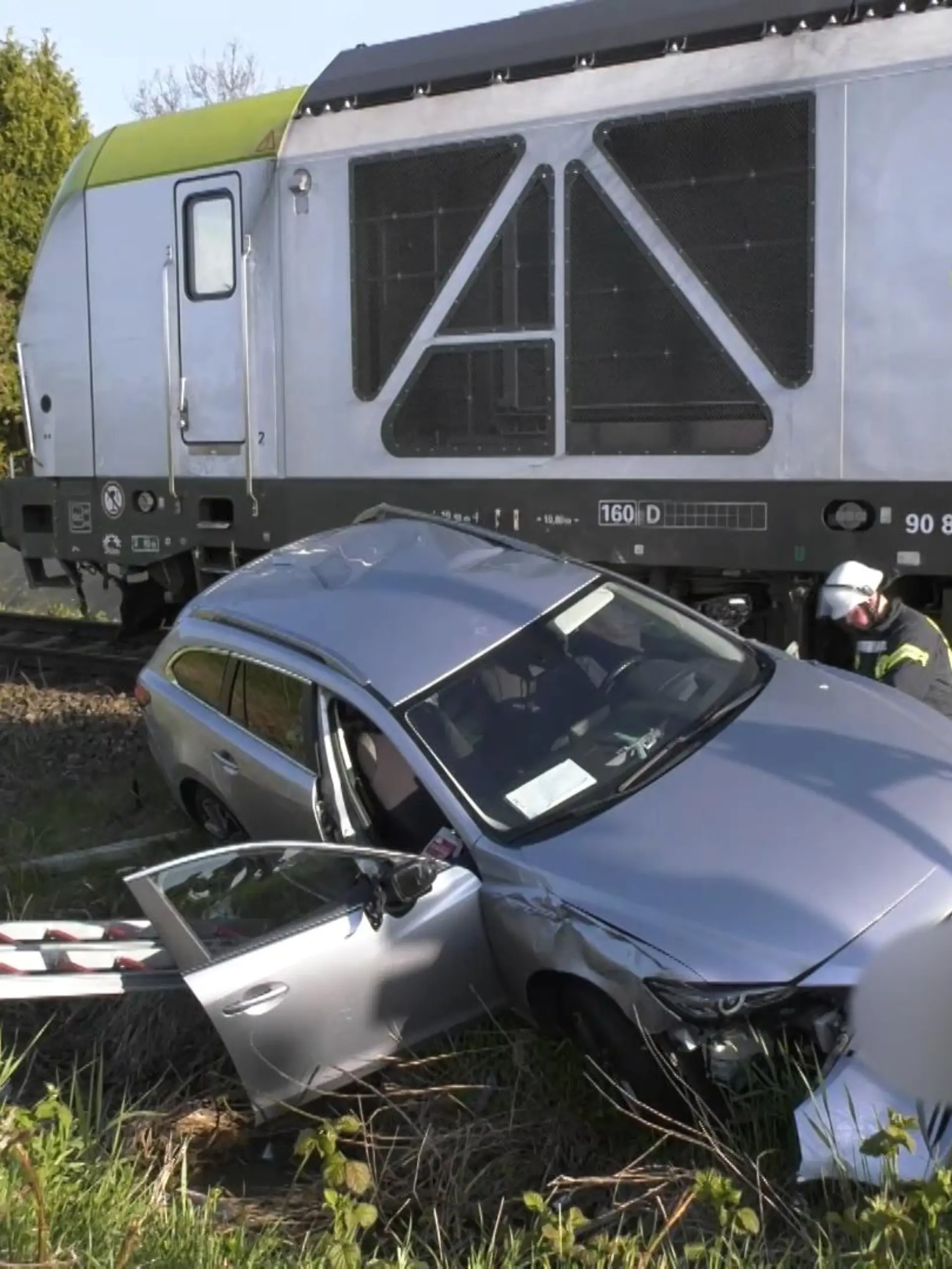 Ein grauer Mazda steht am Bahnübergang in Emden nach dem Unfall mit einem Güterzug neben den Gleisen.