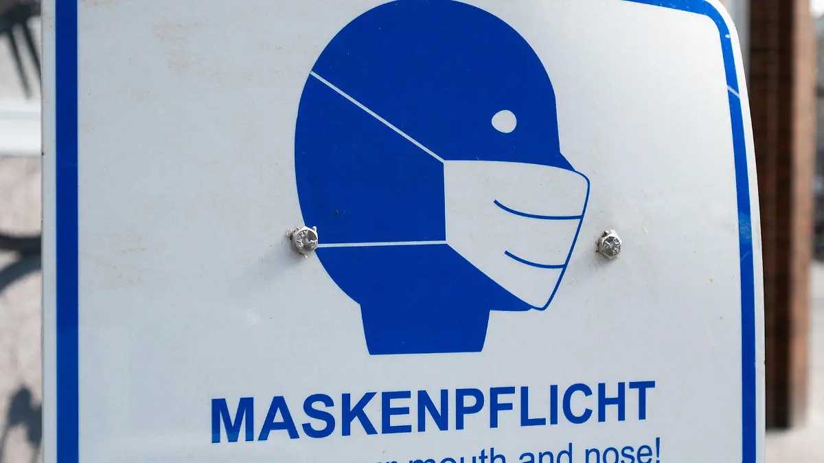 29.03.2021, Hamburg: Passanten gehen in der Innenstadt an einem Schild mit der Aufschrift "·Maskenpflicht"· vorbei. Seit Mitternacht gilt in Hamburg eine neue Corona-Verordnung. Mit der Verfügung verlängert der Senat den Lockdown bis zum 18. April 2021. Foto: Daniel Reinhardt/dpa +++ dpa-Bildfunk +++