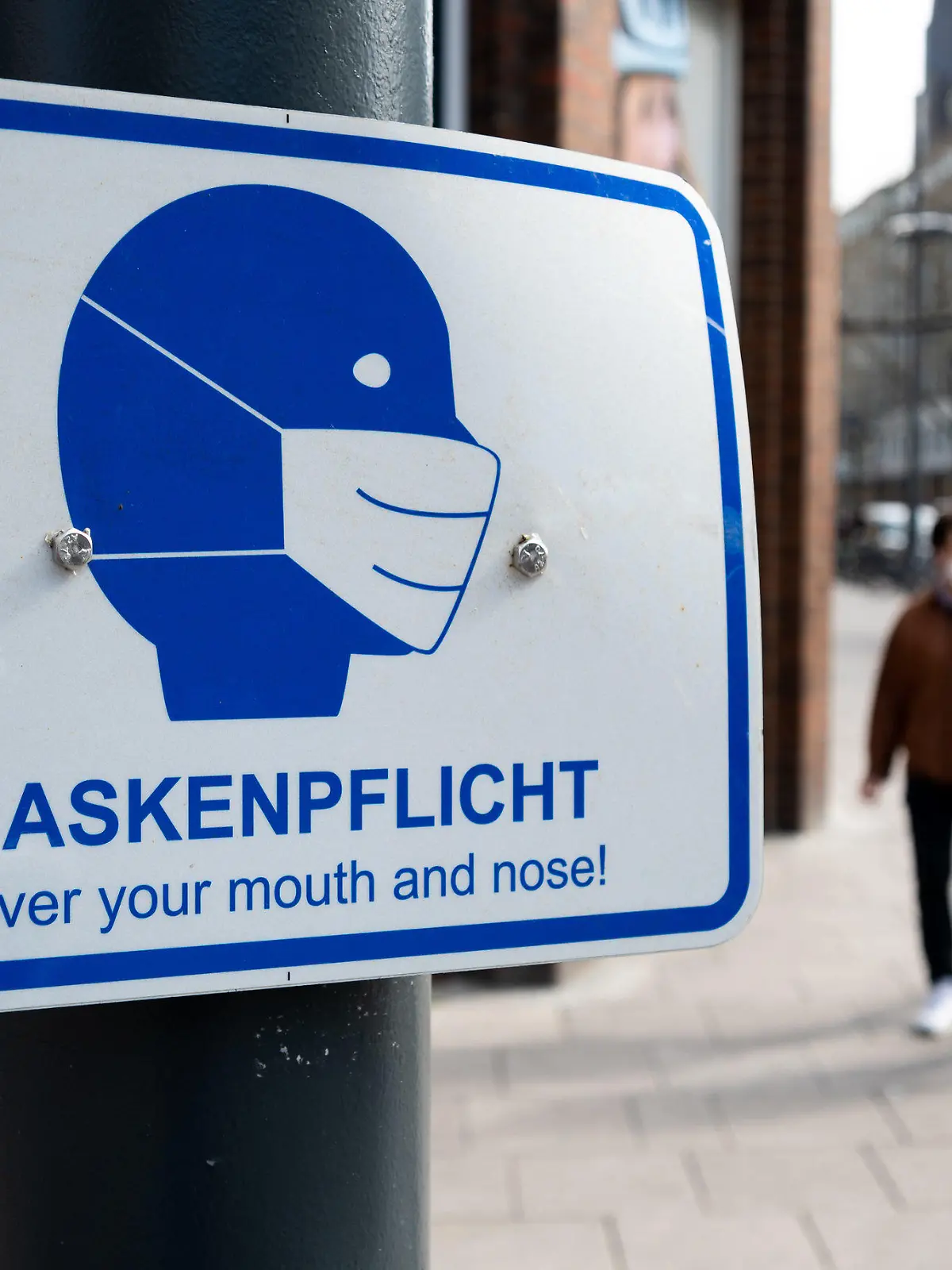 29.03.2021, Hamburg: Passanten gehen in der Innenstadt an einem Schild mit der Aufschrift "·Maskenpflicht"· vorbei. Seit Mitternacht gilt in Hamburg eine neue Corona-Verordnung. Mit der Verfügung verlängert der Senat den Lockdown bis zum 18. April 2021. Foto: Daniel Reinhardt/dpa +++ dpa-Bildfunk +++