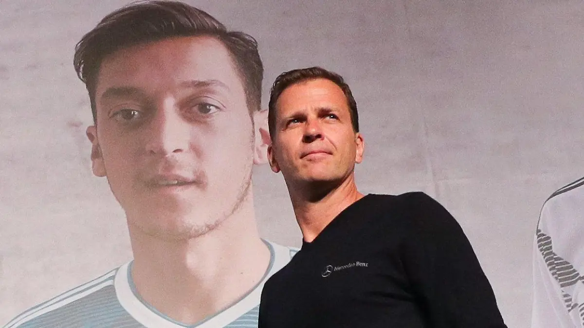 ARCHIV - 15.06.2018, Russland, Watutinki: Fußball, WM, Pressekonferenz der deutschen Fußball-Nationalmannschaft: Team-Manager Oliver Bierhoff geht an einem Poster mit dem Spieler Mesut Özil vorbei auf das Podium zu einer Pressekonferenz im Medienzentrum im Watutinki Hotel (Recrop). (zu dpa «DFB-Direktor Bierhoff hofft auf Treffen mit Özil») Foto: Christian Charisius/dpa +++ dpa-Bildfunk +++