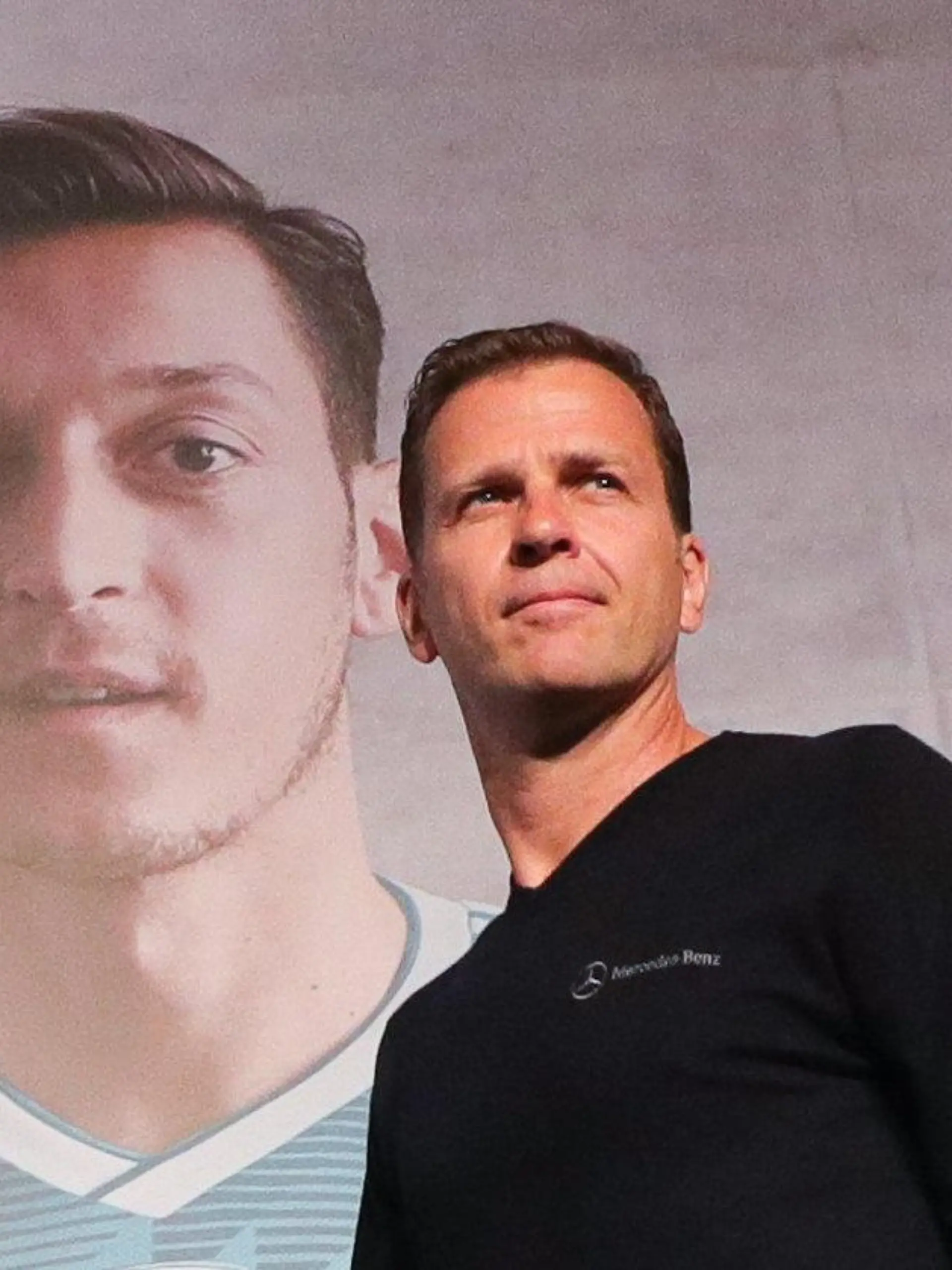 ARCHIV - 15.06.2018, Russland, Watutinki: Fußball, WM, Pressekonferenz der deutschen Fußball-Nationalmannschaft: Team-Manager Oliver Bierhoff geht an einem Poster mit dem Spieler Mesut Özil vorbei auf das Podium zu einer Pressekonferenz im Medienzentrum im Watutinki Hotel (Recrop). (zu dpa «DFB-Direktor Bierhoff hofft auf Treffen mit Özil») Foto: Christian Charisius/dpa +++ dpa-Bildfunk +++