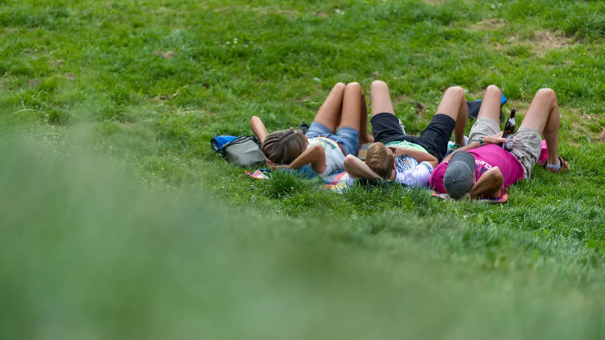 Drei Menschen liegen nebeneinander auf einer Wiese im englischen Garten in Münschen
