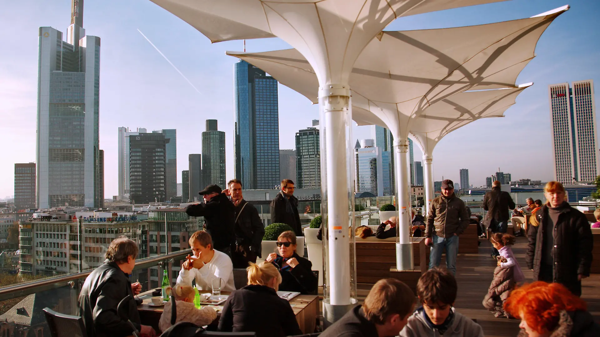 Cafebesucher und Touristen genießen den warmen Novembertag auf einer Dachterrasse bei strahlendem Sonnenschein in Frankfurt am Main am Samstag (19.11.2011). Im Hintergrund sind die Hochhäuser der Banken zu sehen. Nach Aussagen der Meteorologen soll das Wetter in den nächsten Tagen in Hessen immer wieder auch sonnige Abschnitte bringen, bei Höchsttemperaturen um 10 Grad. Foto: Wolfram Steinberg dpa/lhe +++(c) dpa - Bildfunk+++