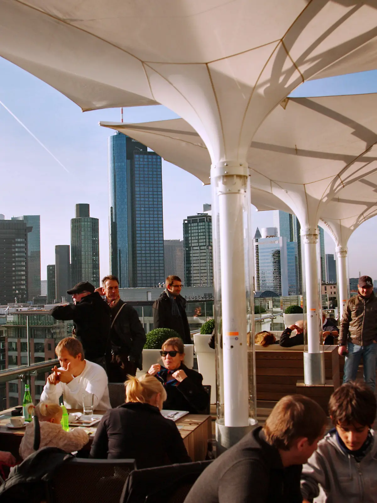 Cafebesucher und Touristen genießen den warmen Novembertag auf einer Dachterrasse bei strahlendem Sonnenschein in Frankfurt am Main am Samstag (19.11.2011). Im Hintergrund sind die Hochhäuser der Banken zu sehen. Nach Aussagen der Meteorologen soll das Wetter in den nächsten Tagen in Hessen immer wieder auch sonnige Abschnitte bringen, bei Höchsttemperaturen um 10 Grad. Foto: Wolfram Steinberg dpa/lhe  +++(c) dpa - Bildfunk+++