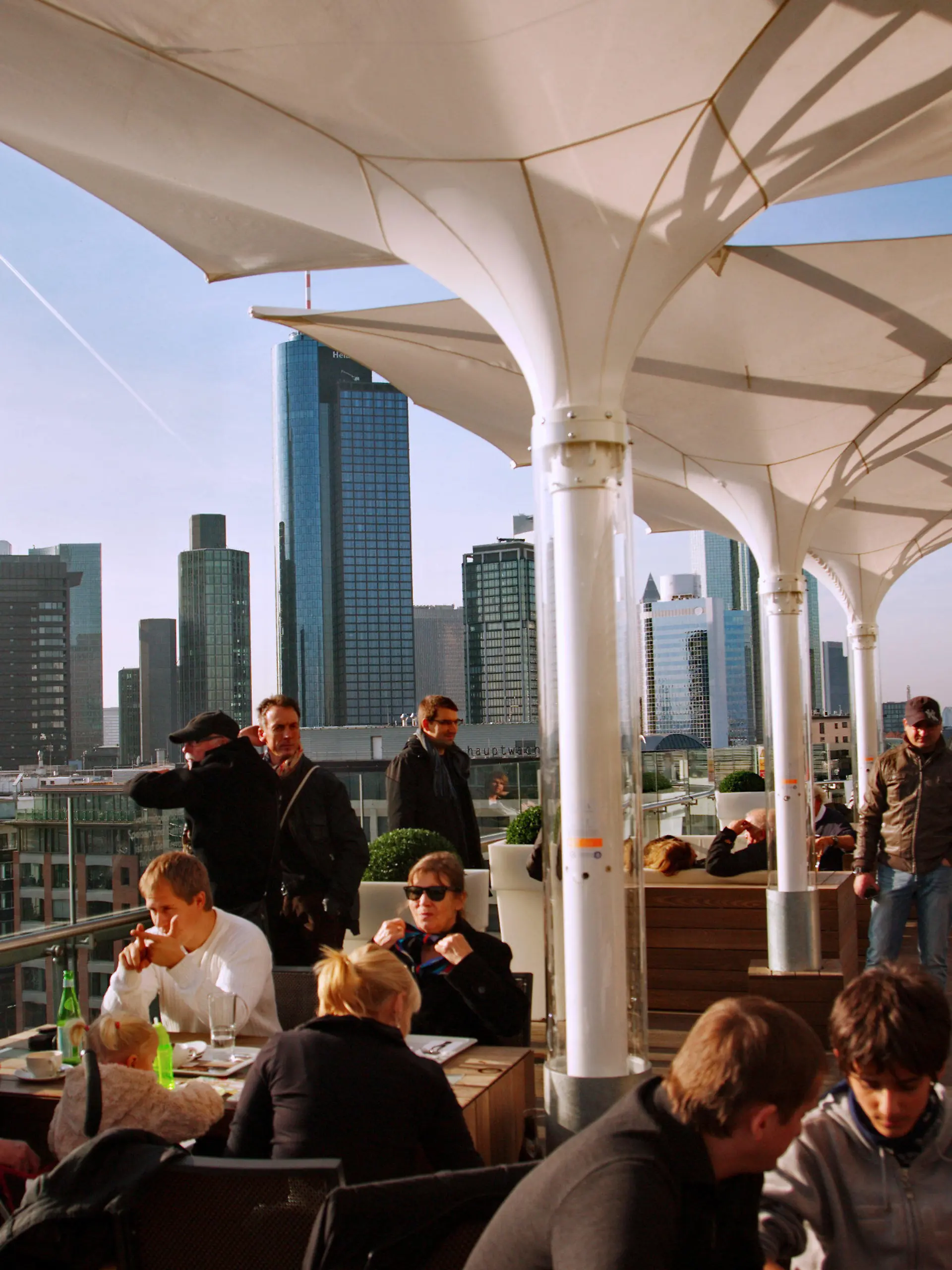Cafebesucher und Touristen genießen den warmen Novembertag auf einer Dachterrasse bei strahlendem Sonnenschein in Frankfurt am Main am Samstag (19.11.2011). Im Hintergrund sind die Hochhäuser der Banken zu sehen. Nach Aussagen der Meteorologen soll das Wetter in den nächsten Tagen in Hessen immer wieder auch sonnige Abschnitte bringen, bei Höchsttemperaturen um 10 Grad. Foto: Wolfram Steinberg dpa/lhe  +++(c) dpa - Bildfunk+++