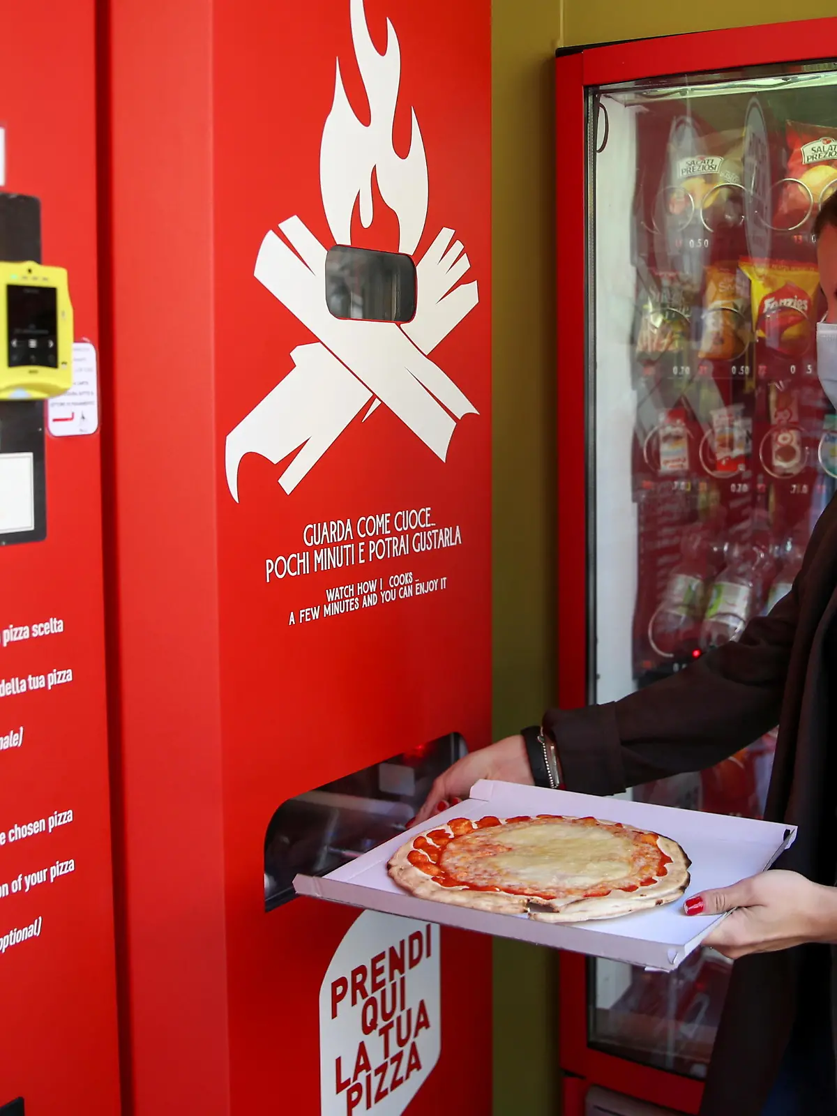 Fabrizia Pugliese collects her order at the first automatic pizza vending machine, which is capable of kneading, seasoning and cooking the pizza in three minutes, in Rome, Italy, May 6, 2021. REUTERS/Yara Nardi