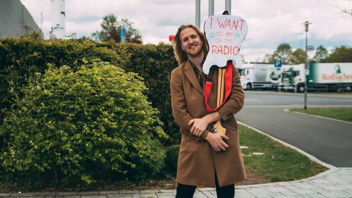 Hartnäckig: Musiker Mika Jones steht mit diesem Schild vor dem hessischen Radiosender planet radio.
