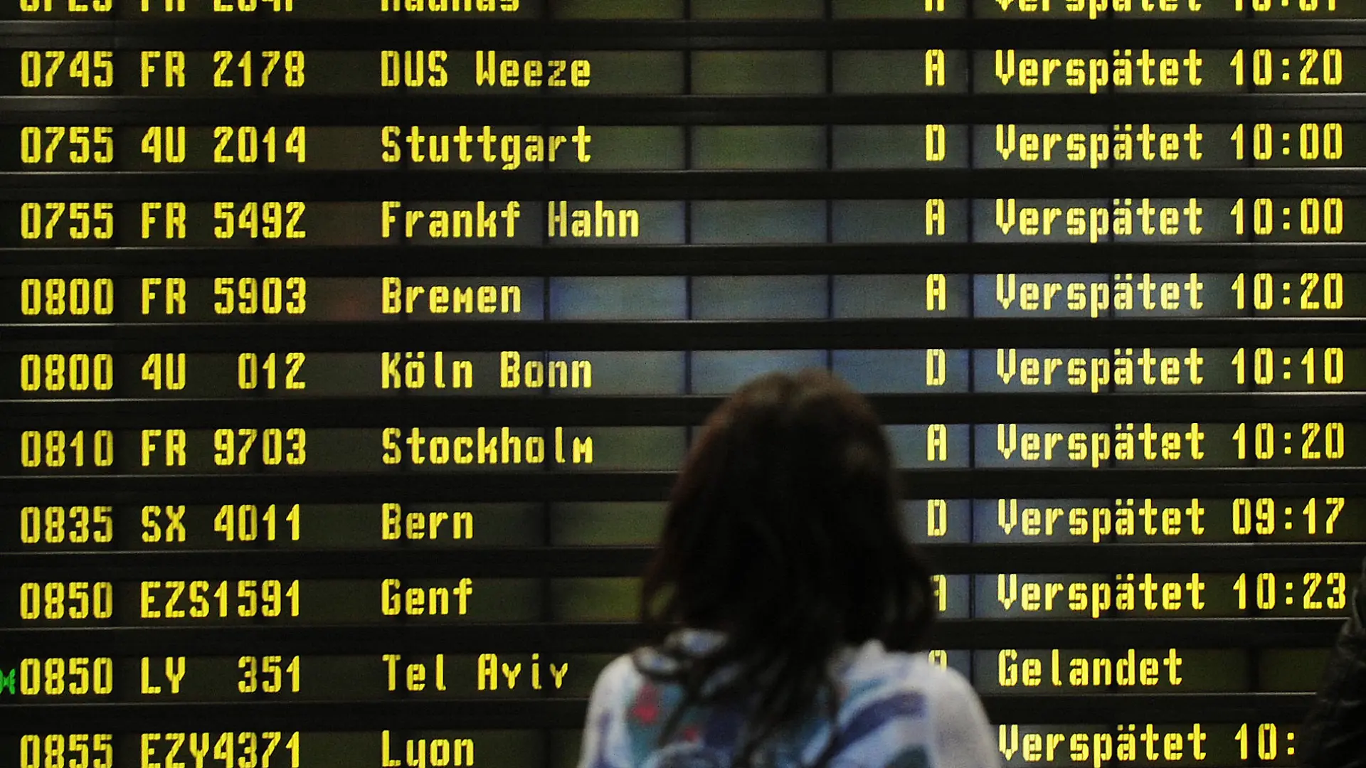 ARCHIV - Eine Frau steht am 10.12.2010 auf dem Flughafen Berlin-Schönefeld vor einer Anzeigetafel, auf der verspätete Flüge angezeigt werden.  Am 04.09. wird ein Urteil des Europäischen Gerichtshofs zu Ausgleichzahlungen bei Flugverspätungen. Foto: Hannibal dpa +++(c) dpa - Bildfunk+++