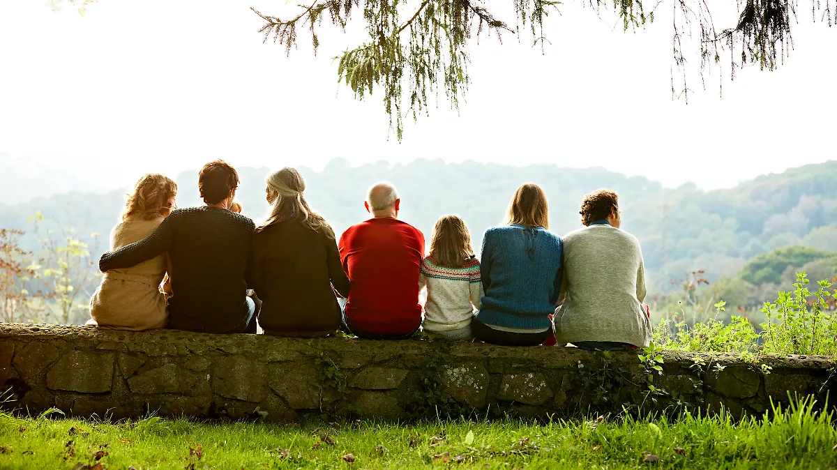 Familie sitzt eng zusammen auf einem Baumstamm.