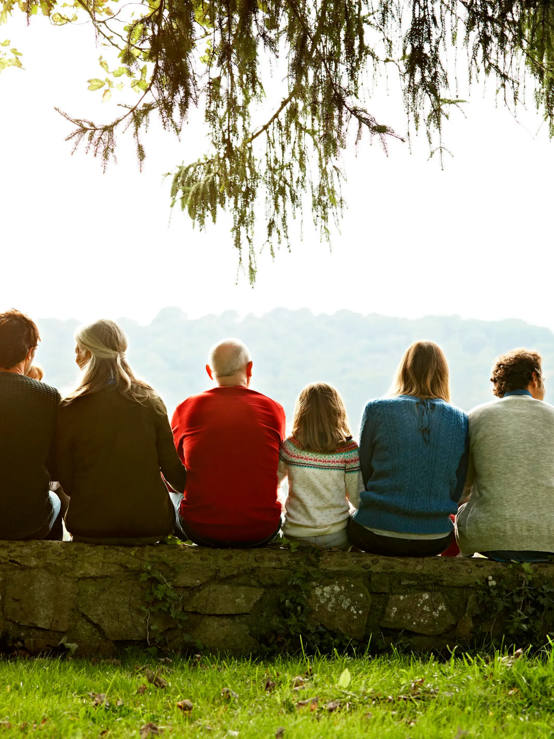 Familie sitzt eng zusammen auf einem Baumstamm.