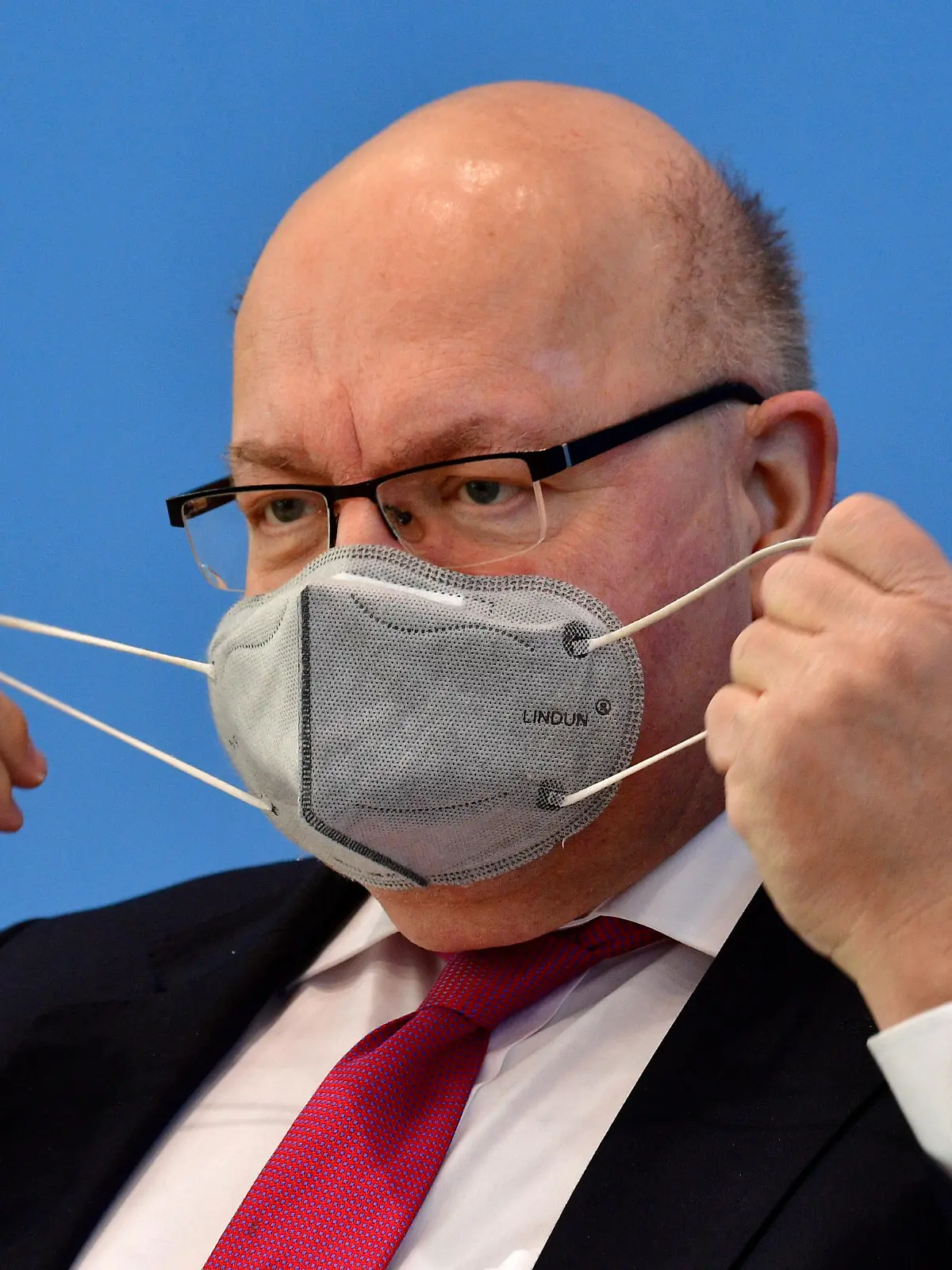 German Economy Minister Peter Altmaier adjusts his face mask as he arrives to present the German government's economic spring projection in Berlin, Germany,  April 27, 2021. John Macdougall/Pool via REUTERS