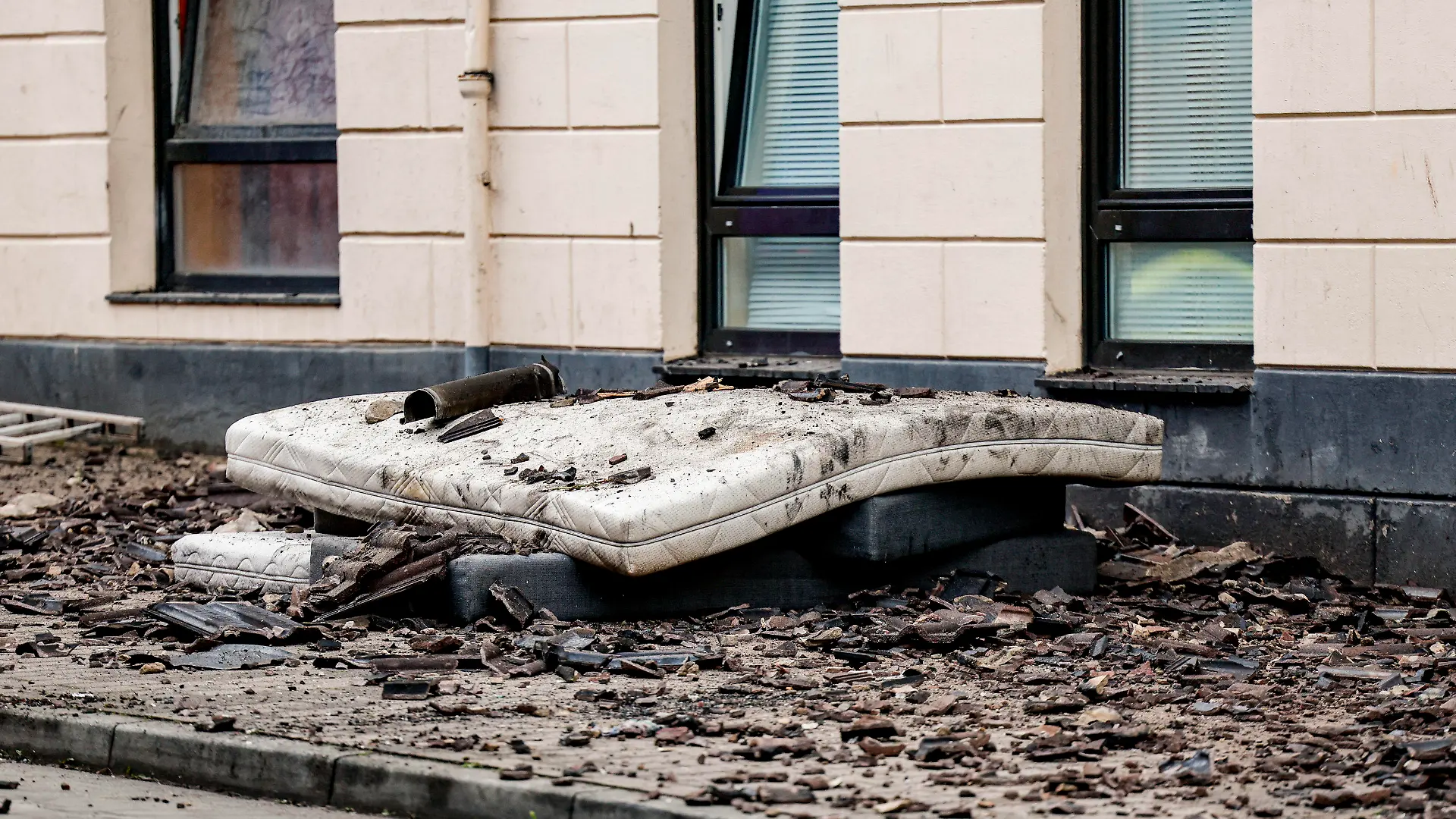 04.05.2023, Schleswig-Holstein, Flensburg: Matratzen, die dazu dienten, Sprünge von Menschen abzufedern, liegen in der Flensburger Neustadt vor einem Haus. Bei dem Brand eines zweieinhalbgeschossigen Mehrfamilienhauses sind zwei Menschen ums Leben gekommen. Foto: Axel Heimken/dpa +++ dpa-Bildfunk +++
