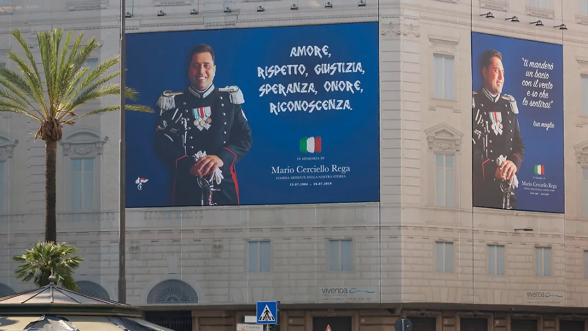 Posters portraying the Italian Carabinieri paramilitary police officer Mario Cerciello Rega, are displayed in the square where he was stabbed to death last year in Rome, Tuesday, July 14, 2020. Posters read in Italian, " Love, respect, justice, hope, honor, gratitude", left, " I'll blow you a kiss in the wind and I know you will feel it. Your wife", right. Two American teenagers are accused of slaying Italian police officer Mario Cerciello Rega on July 26, 2019. Their trial resumed on Wednesday, July 15, 2020. (AP Photo/Domenico Stinellis)