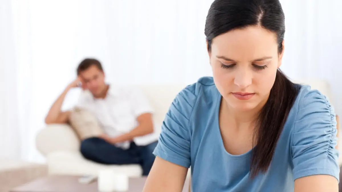 Woman thinking at a table while her boyfriend waiting in the background