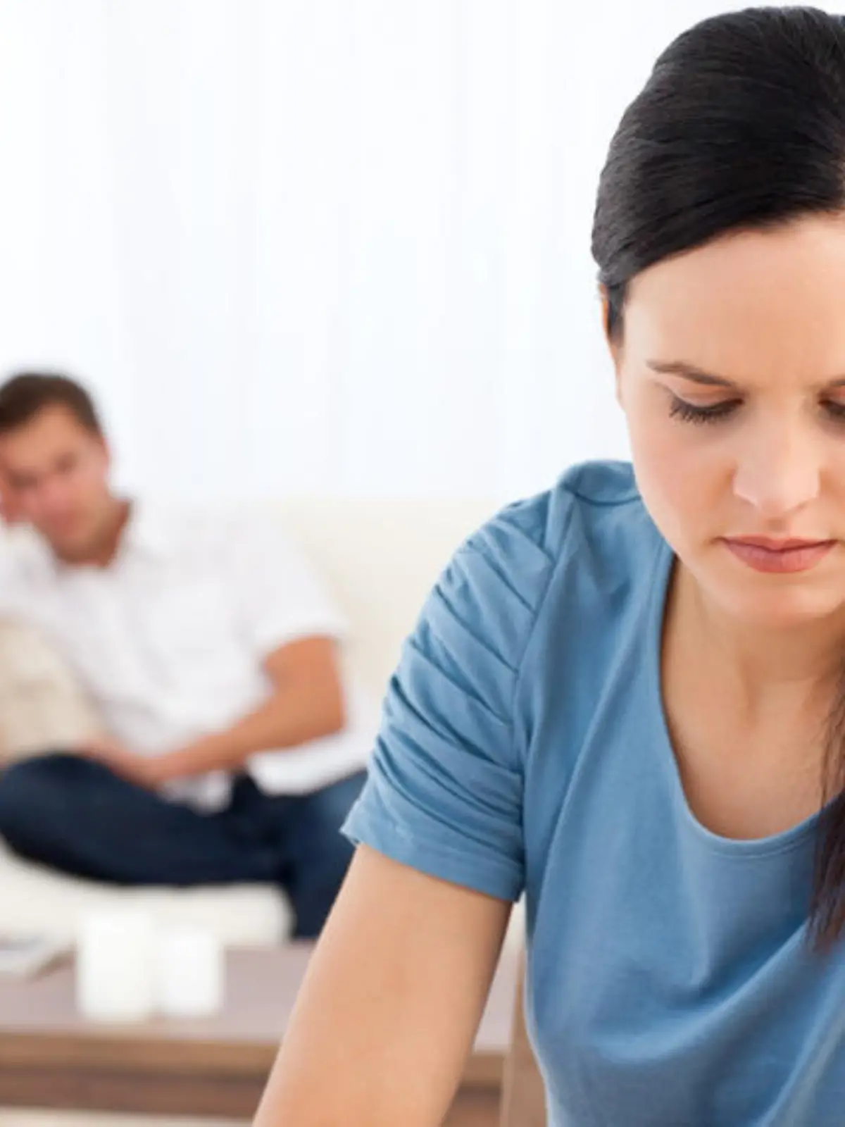 Woman thinking at a table while her boyfriend waiting in the background